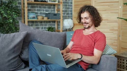 Young Adult Working on Laptop, Relaxing on Sofa