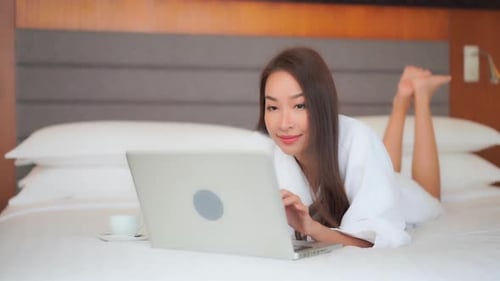 Woman Relaxes and Works on Laptop in Hotel Room