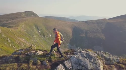 Tourist Hiker with a Backpack in Orange Jacket Walking on Mountain Path in Carpathian Mountains