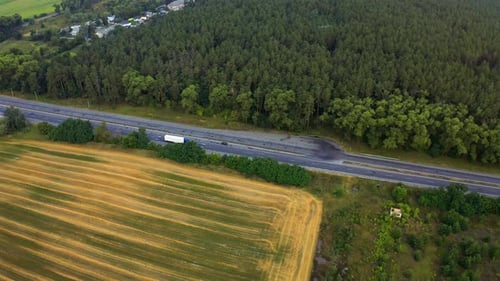 White Truck Rides on the Highway Among a Dense Forest, Traveling on the Forest Asphalt Road Aerial