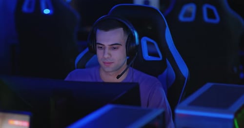 Hombre guapo de apariencia oriental juega en una computadora con auriculares un juego en línea