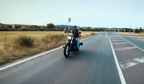 Man Riding Motorcycle Down Country Road