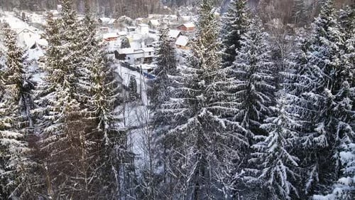 Wunderschöne Enthüllung eines kleinen verschneiten Dorfes hinter dem Winterwald