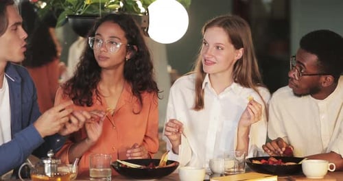 Young Cheerful Friends Having Fun and Laughing While Eating in Modern Cafe. Millennial People