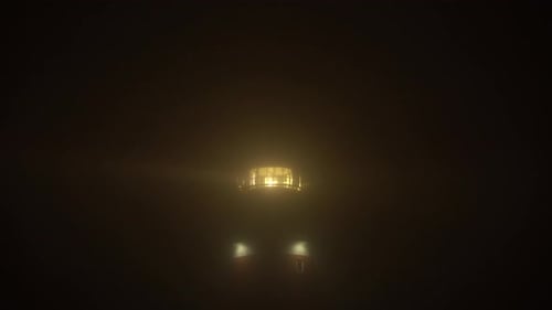 Lighthouse in dense fog with large beams penetrating through the mist