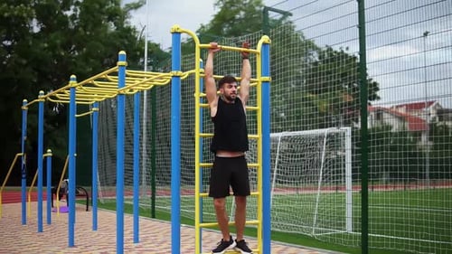 Man Training Core Muscles with Leg Lift on Vertical Ladder Rack on an Outdoors Gym Center