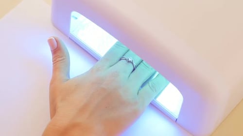 Woman Curing Gel Nails with UV Light