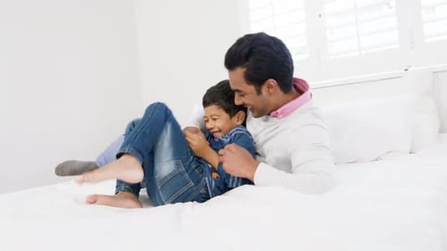 Adult and Child Laughing Together on a White Bed