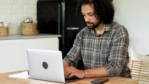 Happy indian man with laptop computer working at home office. Young indian student or remote