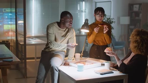 Diverse Colleagues Eating Pizza in Office at Night