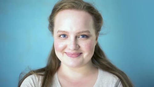 Smiling Woman with Freckles Portrait Against Blue Backdrop