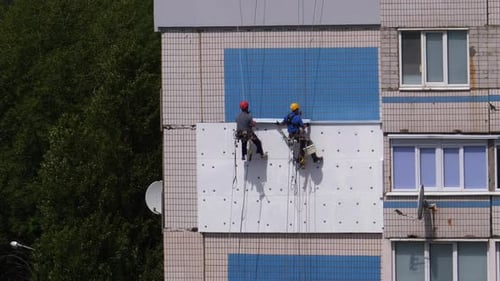 Dois alpinistas industriais, fachada de isolamento de prédio alto usando isopor