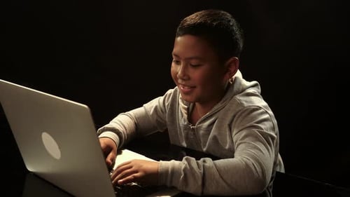 Glücklich lächelnder Hacker-Junge mit Laptop