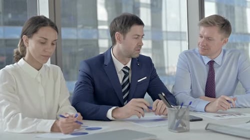 Middle Aged Businessman Having Explaining Things To His Assistants on Office Table