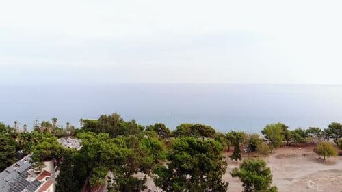 Drohnenschießen eines Ferienortes zwischen Palmen an der Küste und einer wunderschönen Landschaft mit einer Yacht