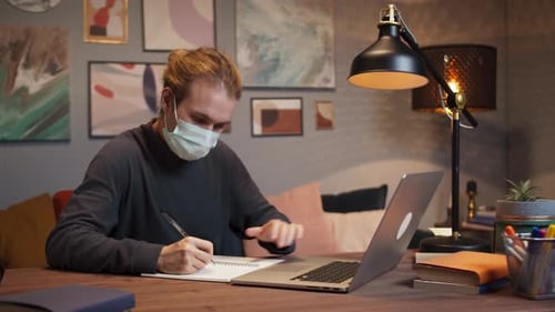 Young Adult Working at Desk with Face Mask