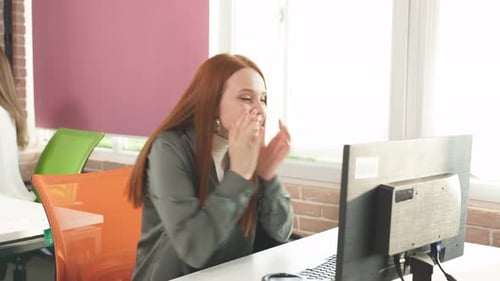 Excited Young Woman Celebrating Work Success at Desk