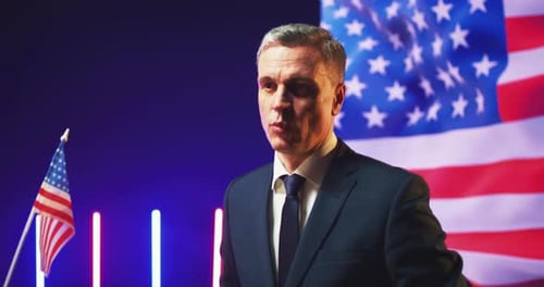 Man Speaks with Flag Backdrop Giving Victory Salute