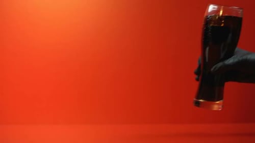 Glass of Dark Soda on Red Background
