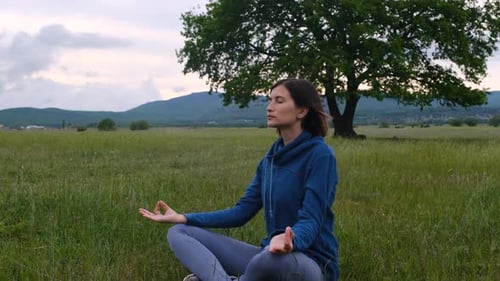 Woman Meditating Outdoors in Grassy Field