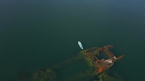Paddleboarder near the Shipwreck in Green Waters