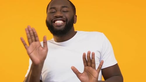 Man Laughing and Gesturing Against Yellow Background