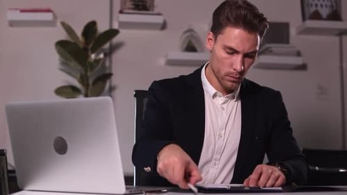 Businessman Writing and Working with Laptop Sitting at Table in Modern Office Spbi