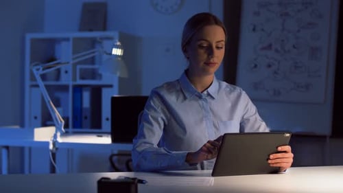 Businesswoman with Tablet and Files at Dark Office