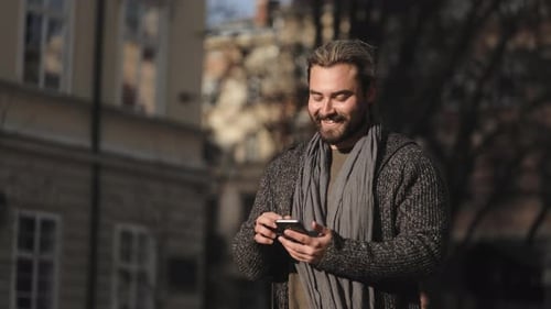 Smiling Man Using Phone in Urban Setting