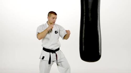 Young Adult Practices Karate Punches on Punching Bag