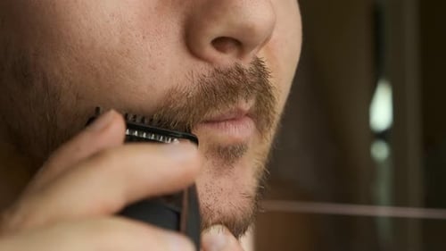 Close Up Man Shaving Mustache and Beard with an Electric Razor.