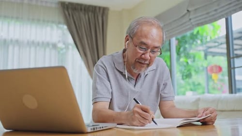 Home office of Asian Senior elderly business man working online with laptop computer at home.