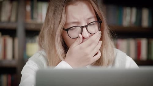 Little Schoolgirl Yawns Looking at Laptop Screen