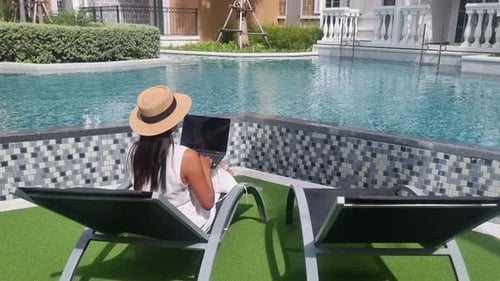Asian Women with Hat Checking Laptop on Holiday Vacation Digital Nomad Concept