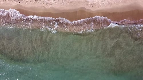 Beautiful aerial view of the drone, the ocean washes the golden shore with these waves.