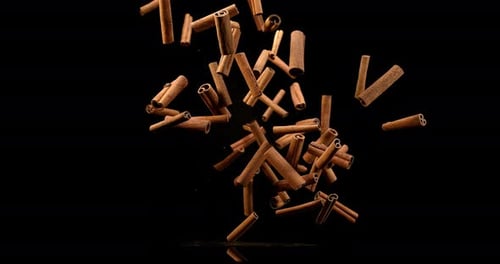Cinnamon sticks, cinnamomum zeylanicum, spice falling against Black Background, Slow Motion 4K