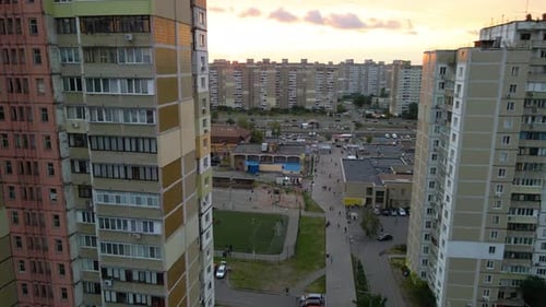 Vista aérea entre antiguos edificios de apartamentos de fabricación soviética, que revela un campo de fútbol, en un barrio para indigentes