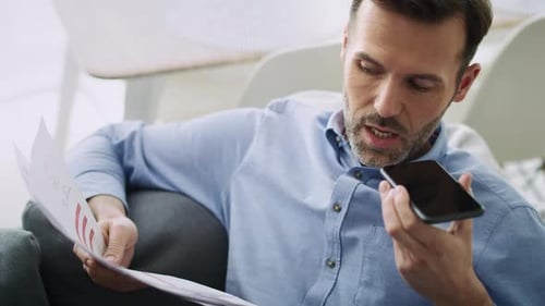 Man Reviewing Documents and Talking on Smartphone