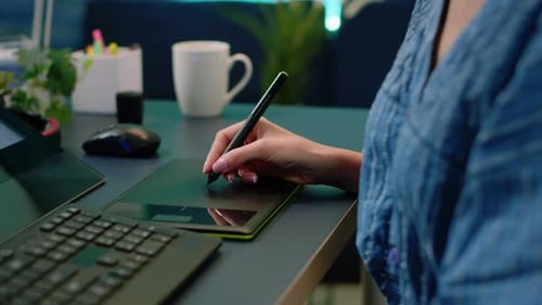 Woman Uses Stylus to Draw on Tablet at Desk