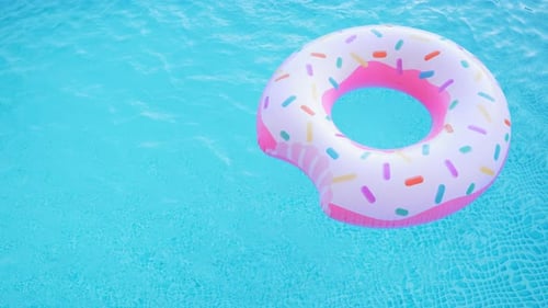 Anel de donut inflável rosa flutuando na piscina azul clara
