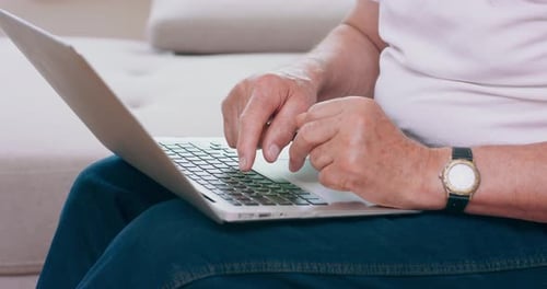Senior Adult Typing on Laptop Computer Indoors