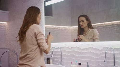 Woman Applies Makeup in Modern Bathroom Setting