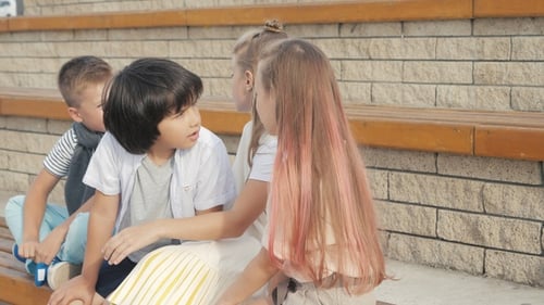 Friends kids sitting and talking outside.