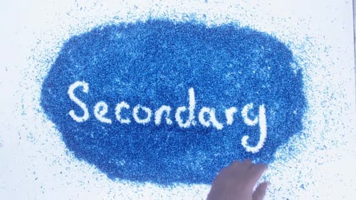 Hand Writes Secondary on Blue Shavings