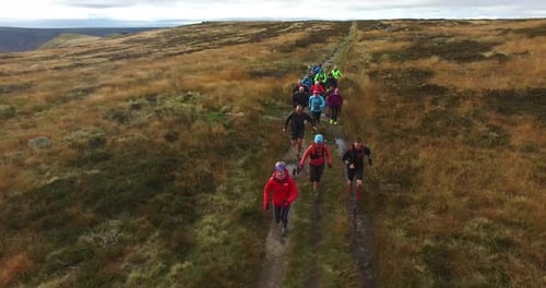 Group Runs Trail in Rural Grassy Landscape