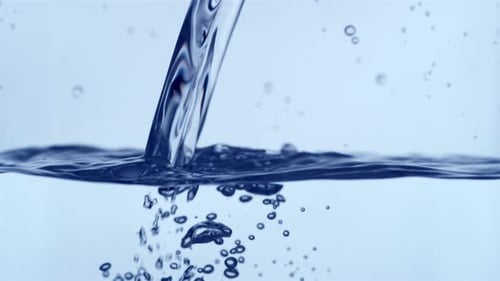 Clear Liquid Pouring into Water, Forming Bubbles