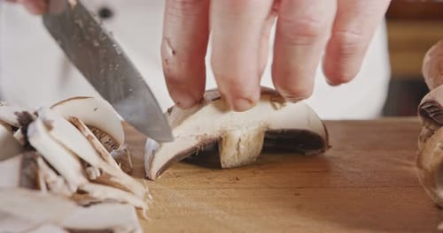 Gros plan d'un couteau de chef tranchant un champignon portobello