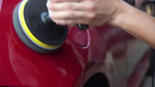 Man Buffing Red Car With Electric Buffer
