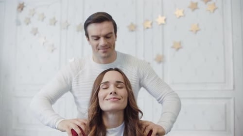 Smiling Couple Relaxing with Massage in Christmas Decorated Room