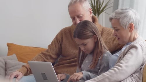 Grandparents and Child Enjoying Laptop Together on Sofa